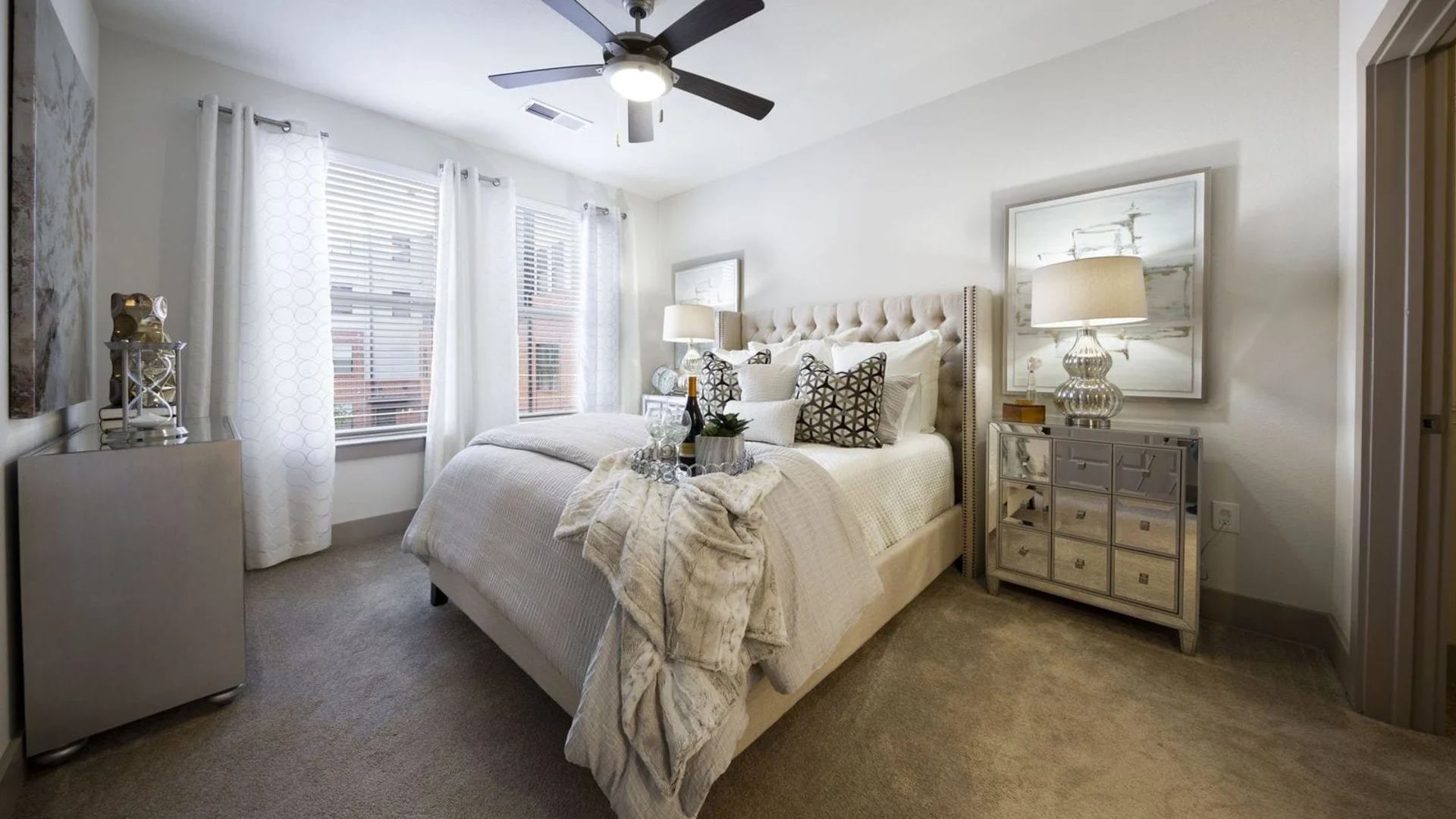 a bedroom with a bed, dresser and ceiling fan at The Steelyard Apartments