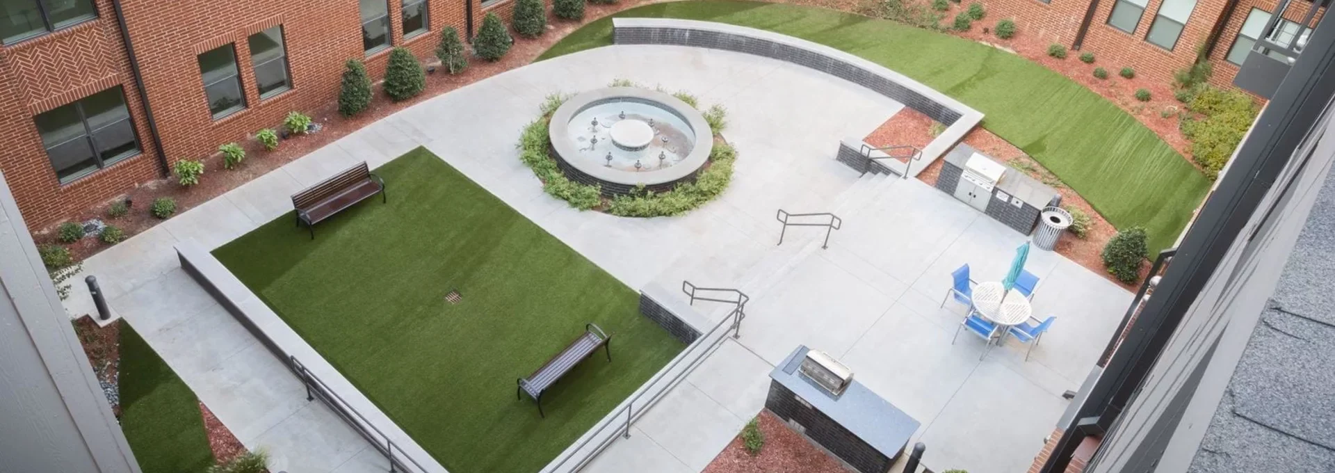 an aerial view of a courtyard with a fountain and a lawn at The Steelyard Apartments