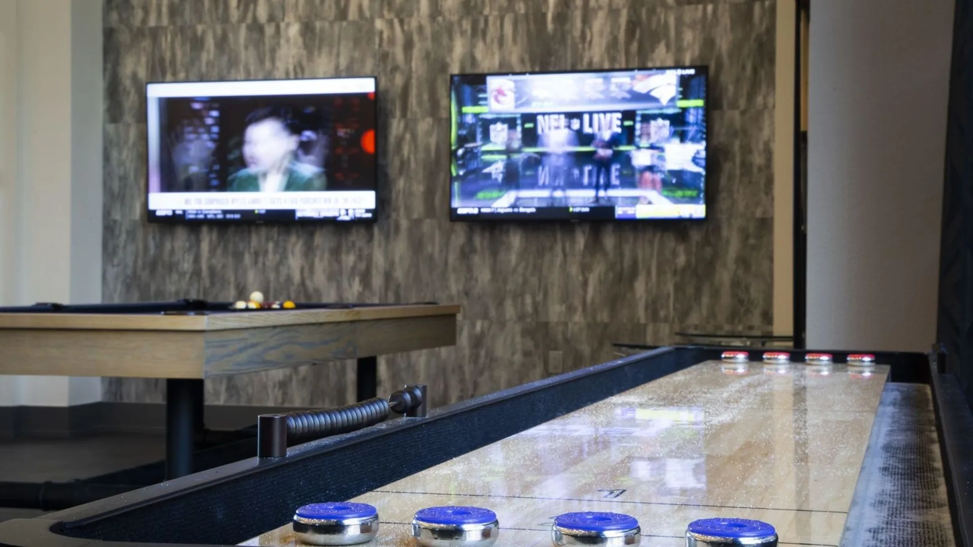 a shuffleboard table with two televisions on the wall at The Steelyard Apartments