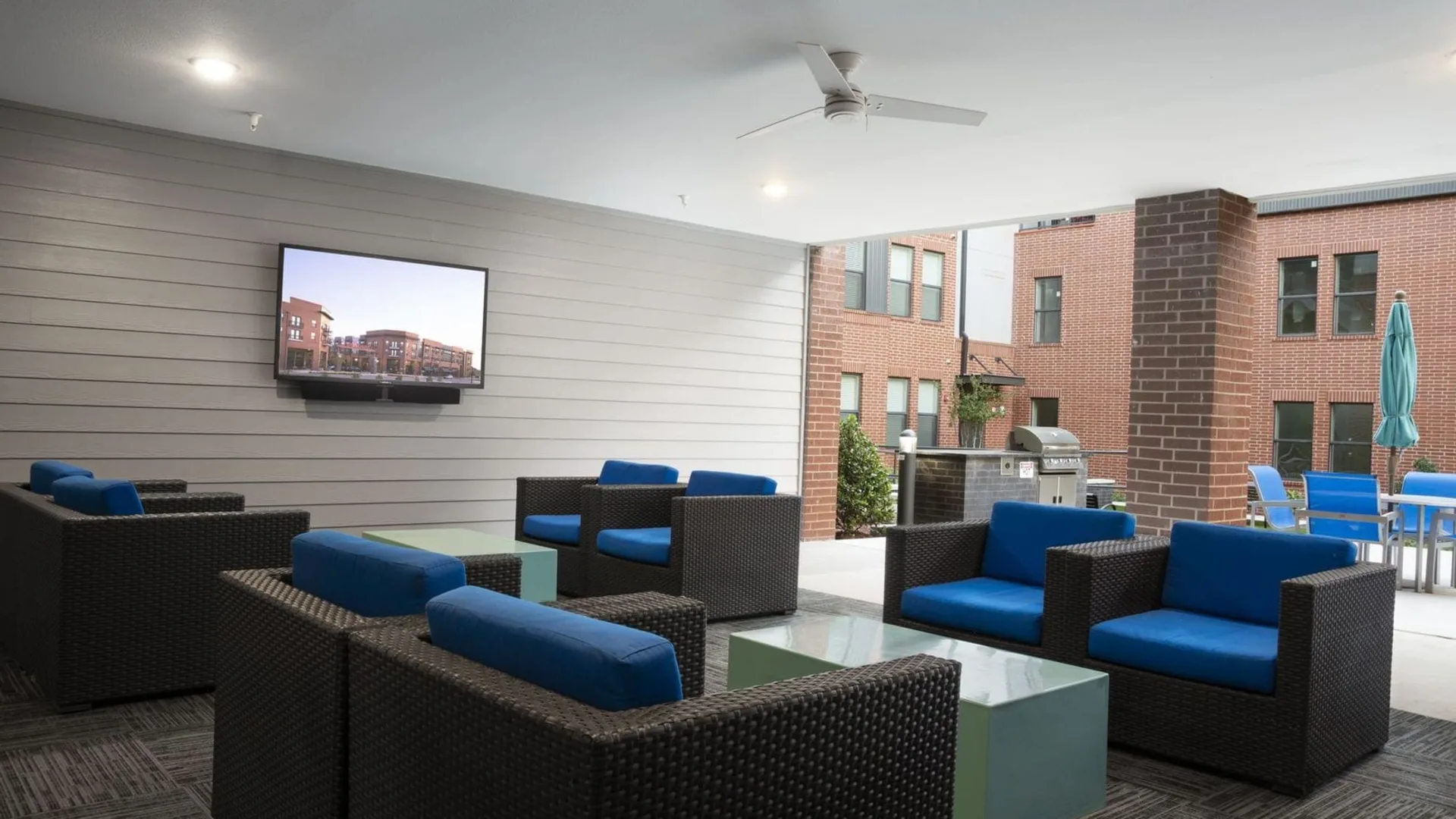 a large outdoor living area with blue couches and a flat screen tv at The Steelyard Apartments