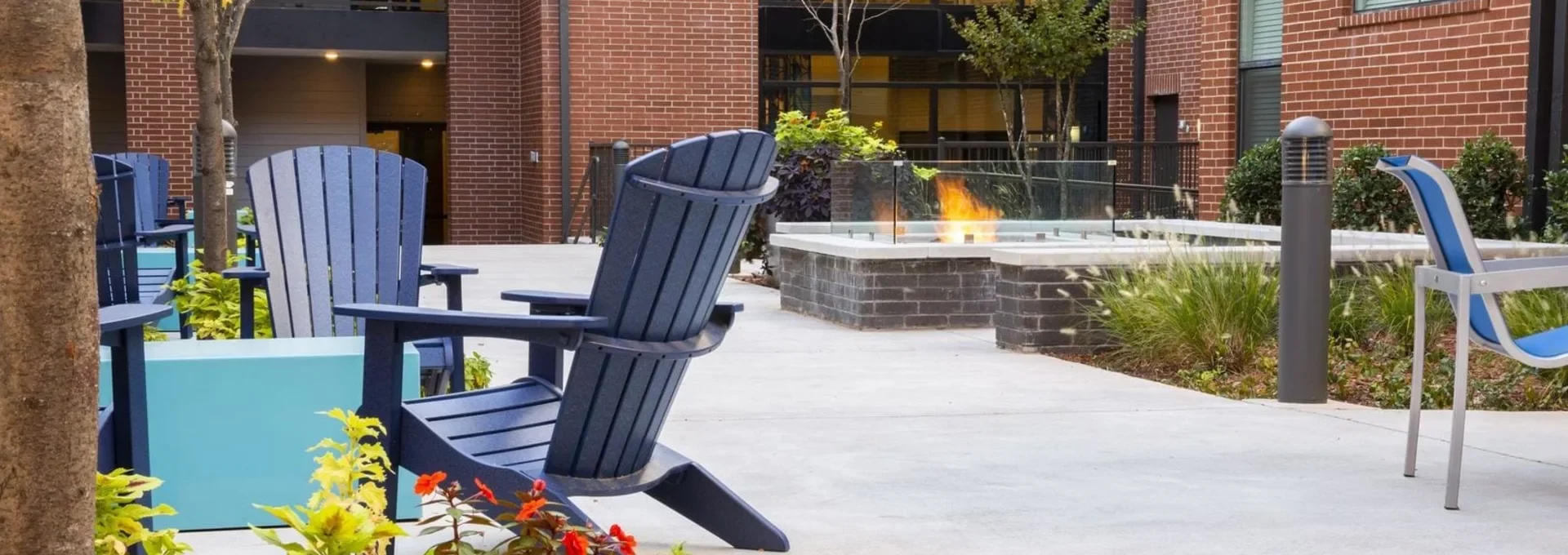 a patio with blue chairs and a fire pit at The Steelyard Apartments