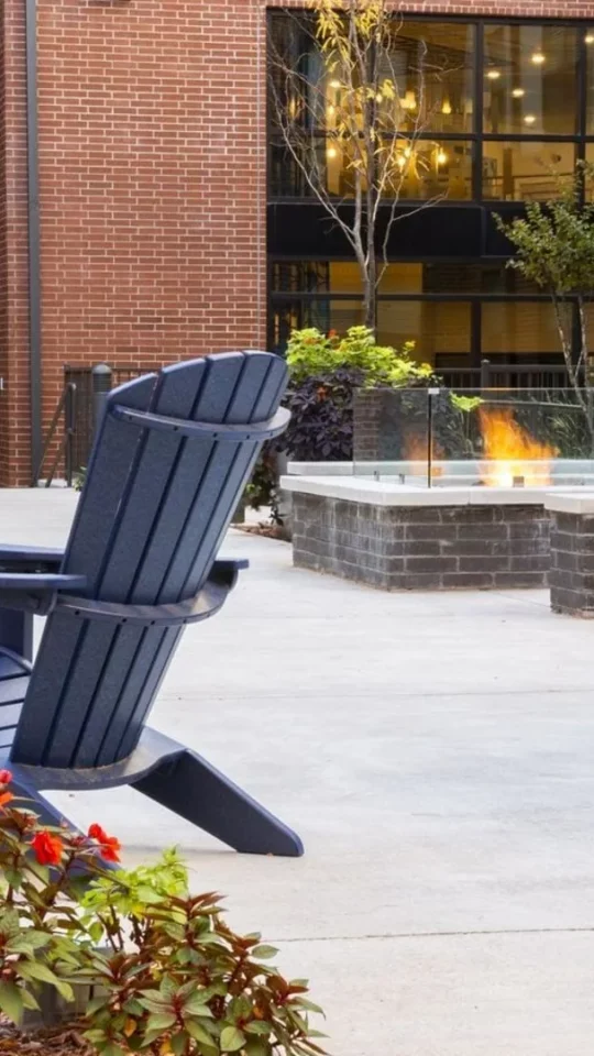 a patio with blue chairs and a fire pit at The Steelyard Apartments