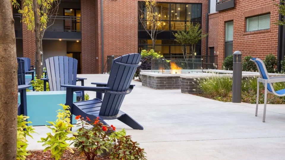 a patio with blue chairs and a fire pit at The Steelyard Apartments