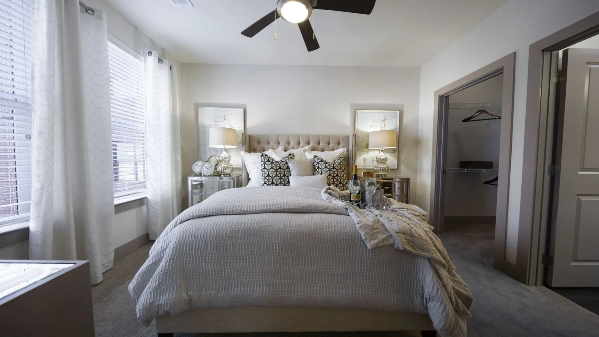 a bedroom with a ceiling fan and white bed at The Steelyard Apartments