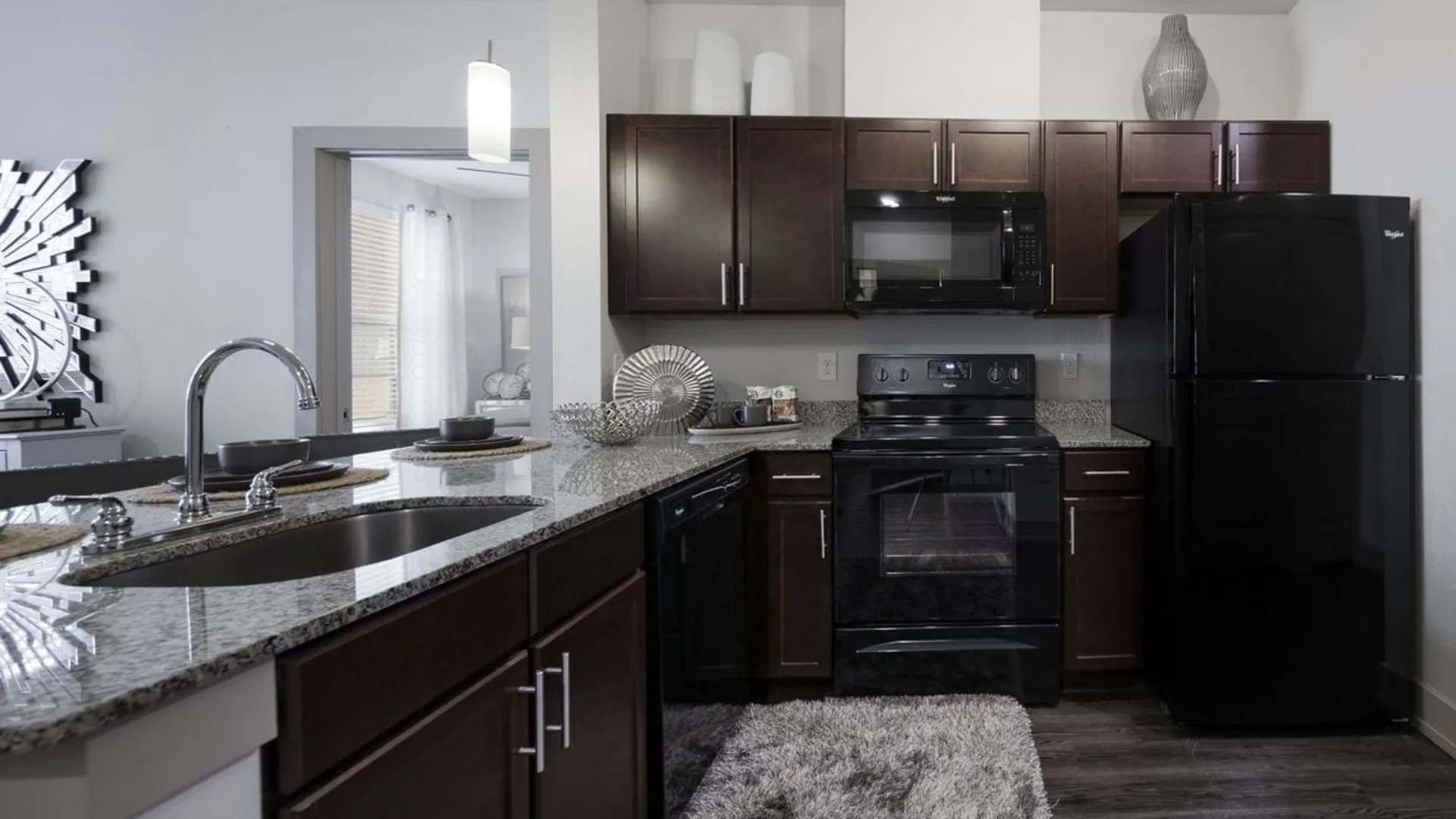 a kitchen with black appliances and dark wood cabinets at The Steelyard Apartments