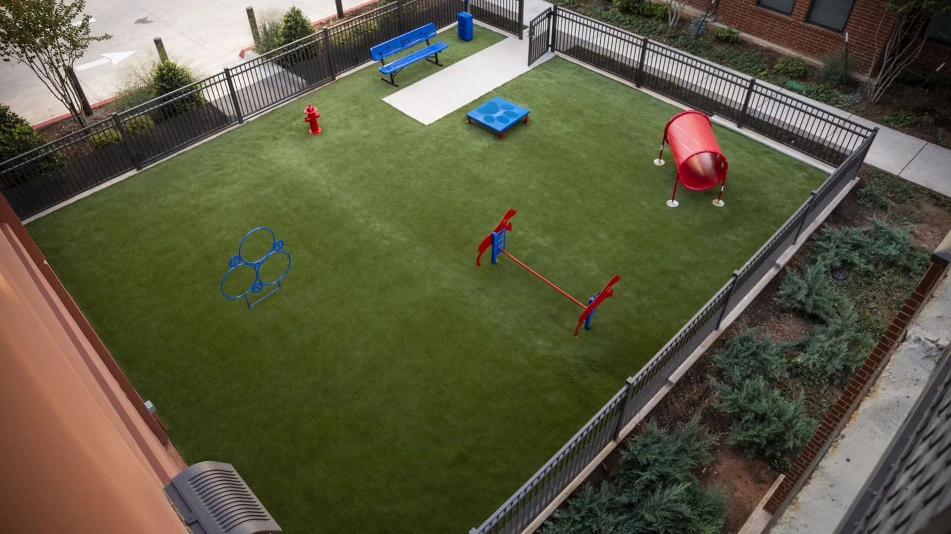 a dog park with artificial grass and a red ball at The Steelyard Apartments