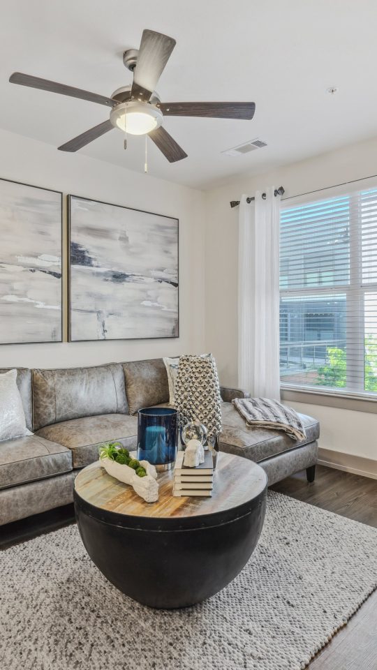 a living room with a ceiling fan and a couch at The Steelyard Apartments