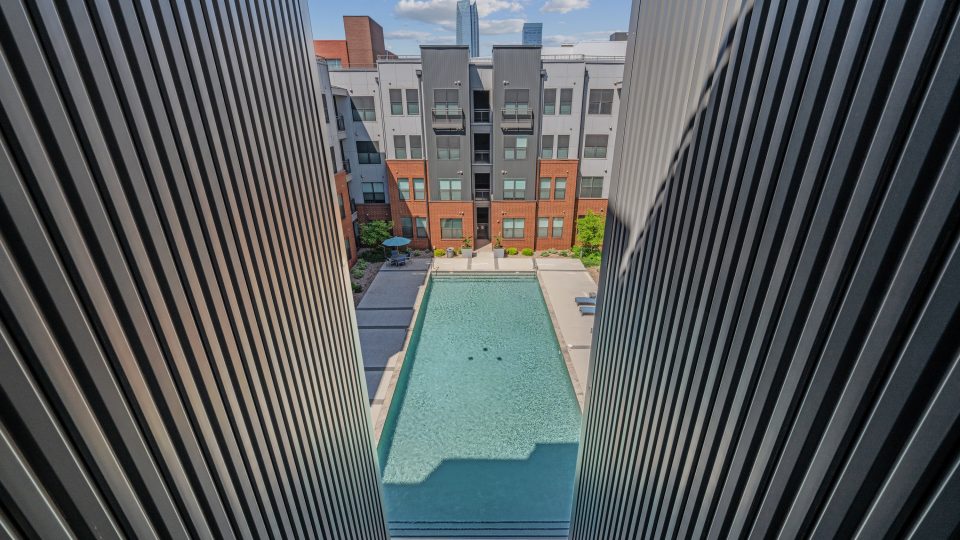 the pool is surrounded by buildings and a fence at The Steelyard Apartments